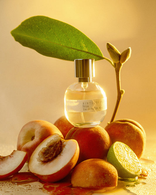 Perfume bottle with fruit and leaves on a warm-toned background